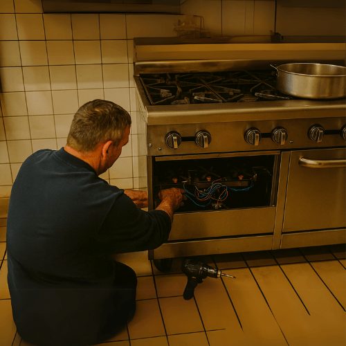 Technician repairing a commercial gas stove in a professional kitchen